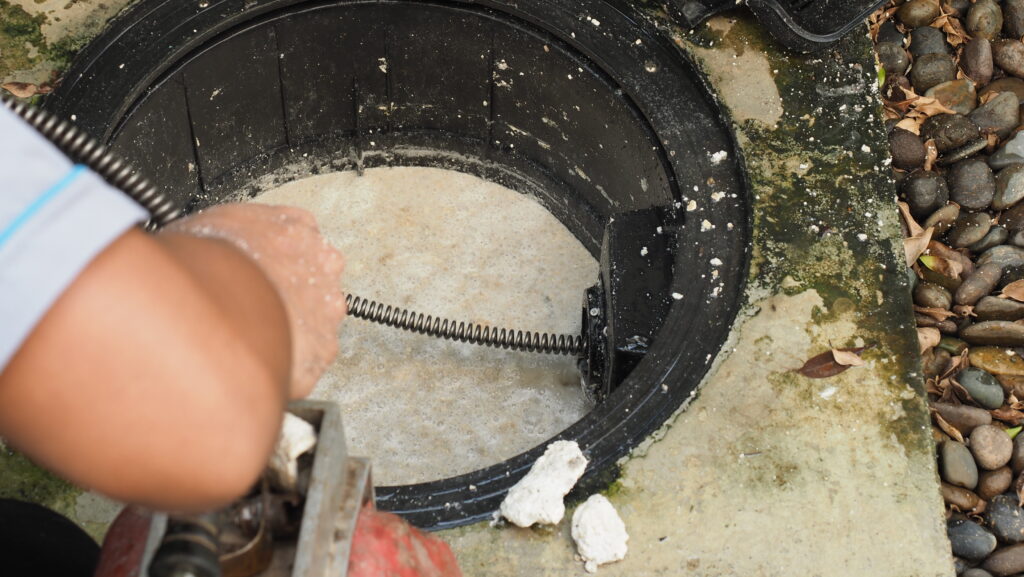 using a drain snake to clear blocked pipes